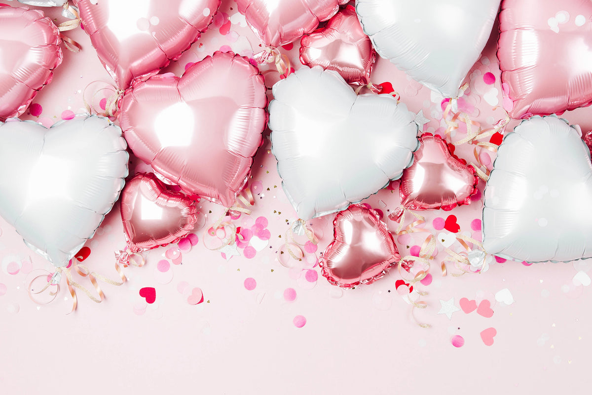 Pink background with a mix of different sized white and pink love heart balloons