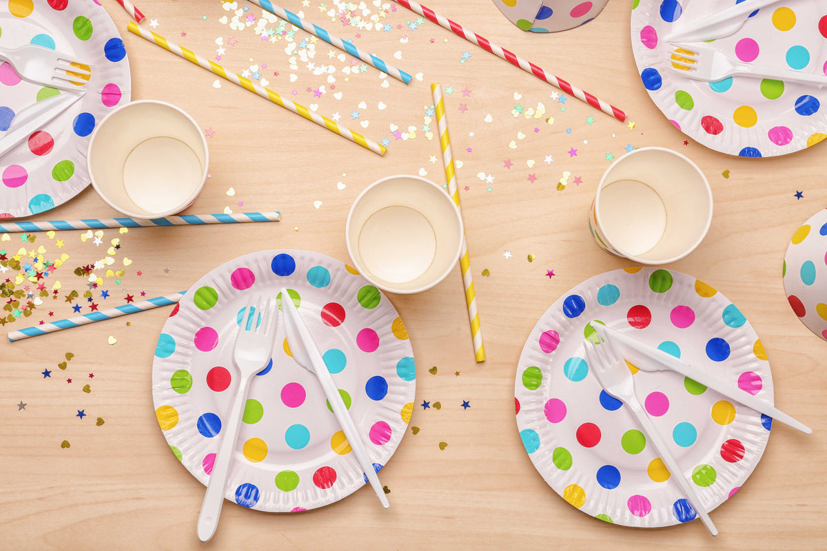 A table with pretty colourful polka-dotted plates, straws and star table sprinkles scattered.